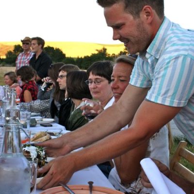 photo of server setting beautiful plate of grilled chicken on table—2011 Outstanding in the Field Dinner—photo by The Farm Chicks